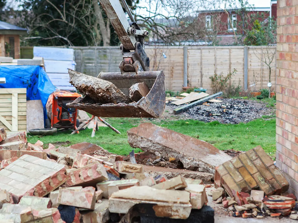 Excavator carrying away demolition debris