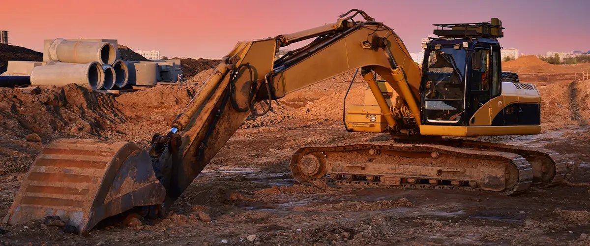 Excavator on earthworks at construction site on sunset backround.