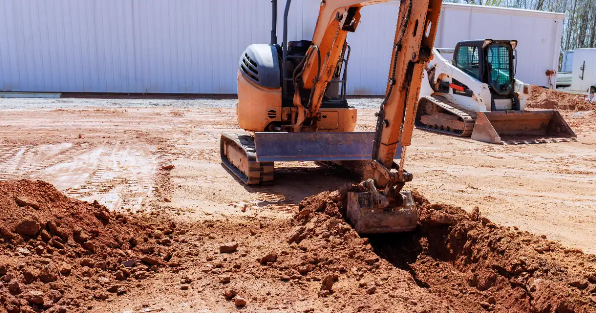 a compact hydraulic excavator and a skid-steer loader working on a construction site