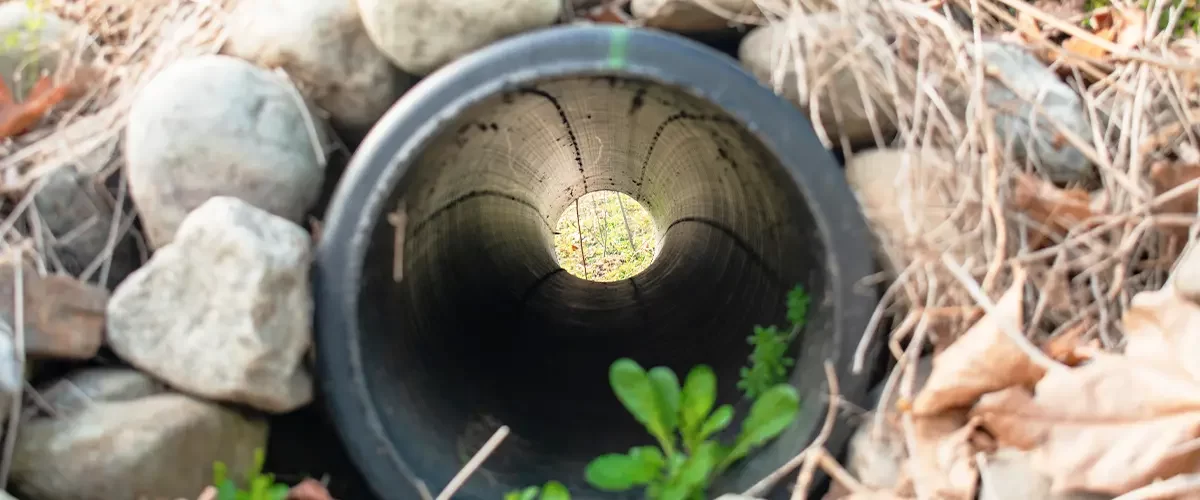 Close-up of a drainage pipe surrounded by rocks in a French drain system